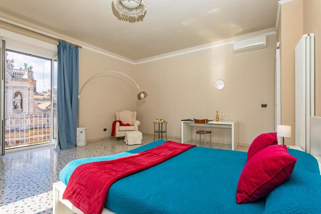 Camera da letto ampia con pavimento in graniglia, copriletto turchese e portafinestra sul balcone con vista sulla Collegiata